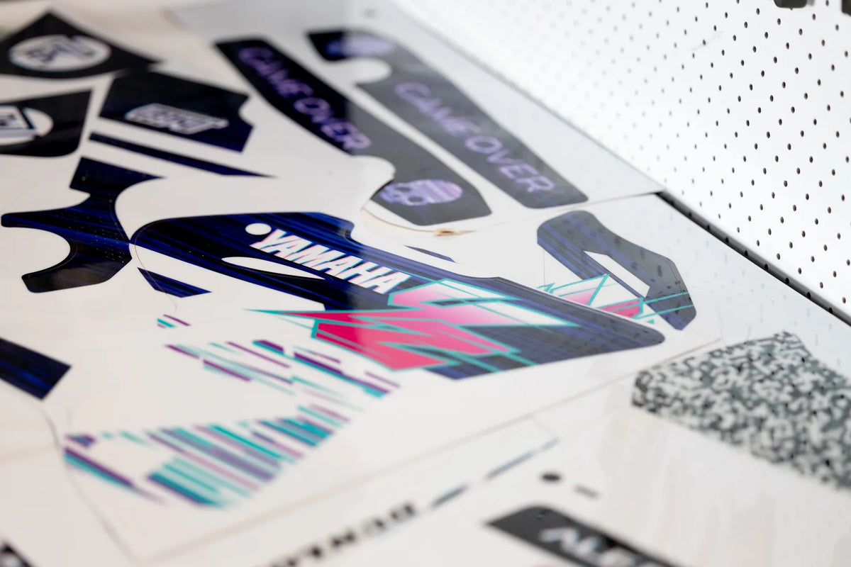 Custom motorcycle graphics laid out on a production work surface.