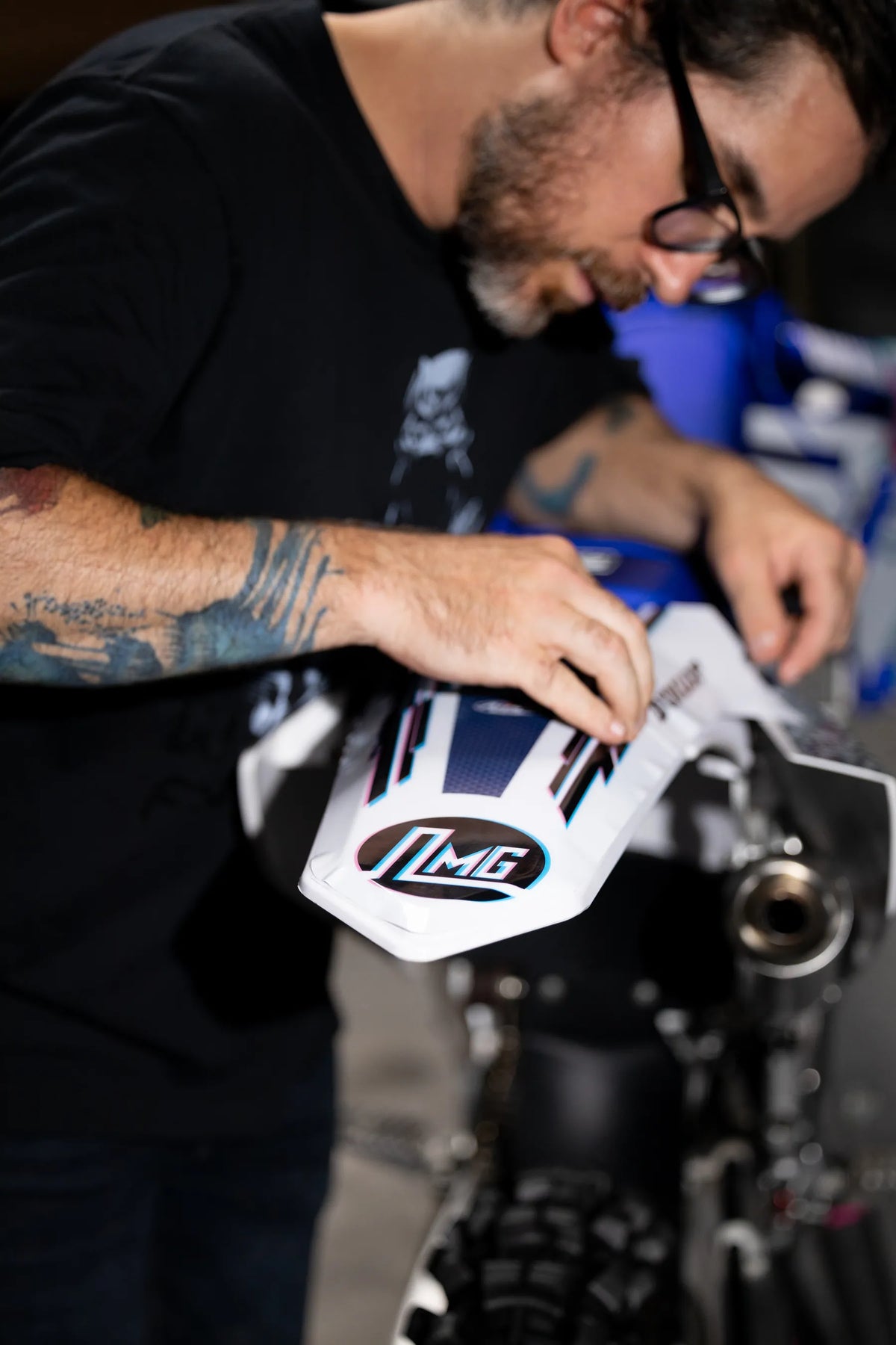 Close-up of hands working with a printed graphic on a white bike panel in the workshop.