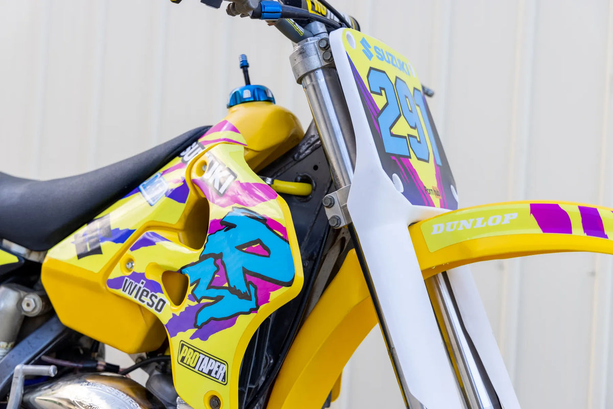 Close-up of yellow and purple custom graphics on a Suzuki motocross bike
