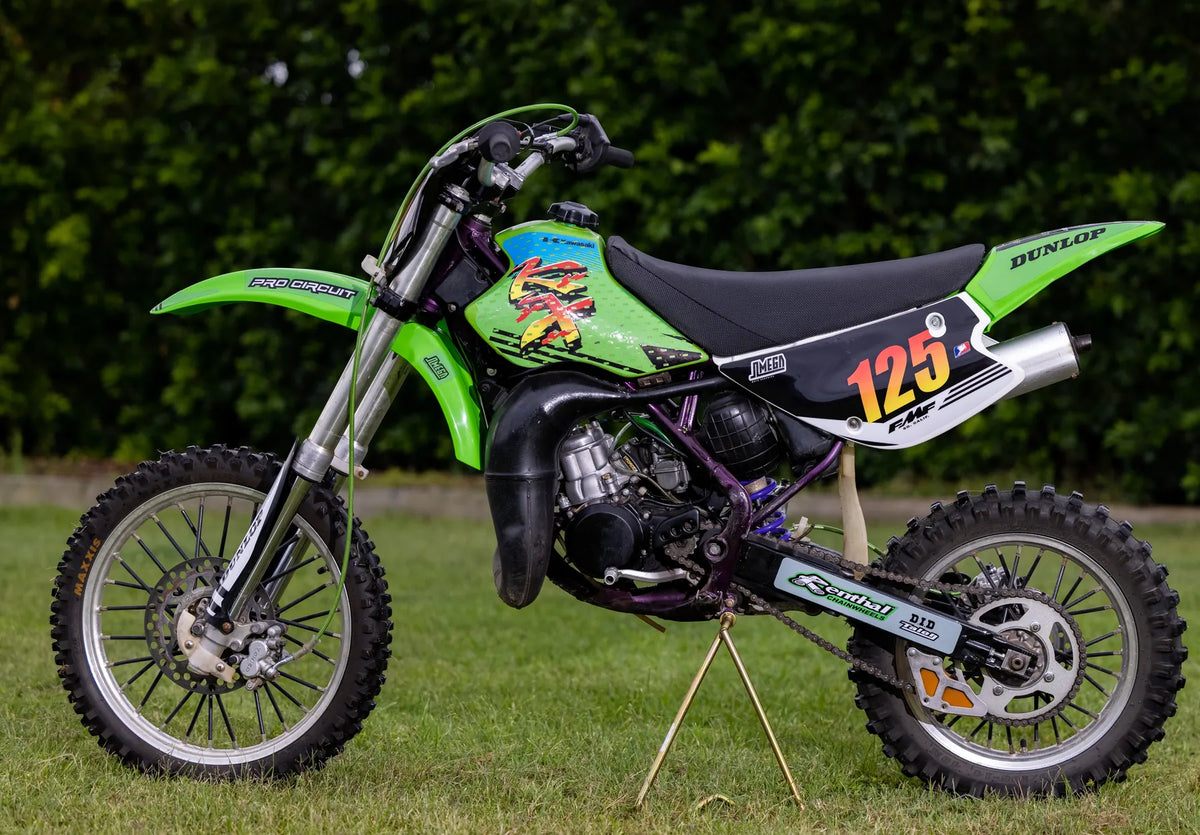 Full side profile of a green Kawasaki KX with custom graphics